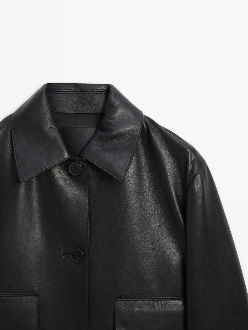 May include: A black leather jacket with a button-up front and two pockets. The jacket has a collar and is made of a soft, supple leather.