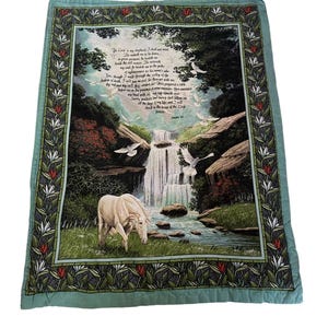 Può includere: Una trapunta quadrata decorativa con una scena pastorale con una cascata, un cavallo bianco e uccelli in volo. Il bordo è verde chiaro con un motivo floreale. Il testo del Salmo 23 è stampato sulla trapunta.