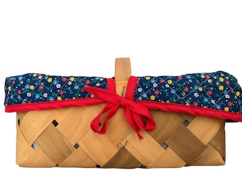 Cesto vintage in legno intrecciato a mano con fodera trapuntata a fiori e bordo rosso, ideale per picnic in stile rustico.