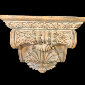 Può includere: Mensola da parete decorativa con un design intagliato e ornato. Dipinta in tonalità beige e marrone, presenta intricati dettagli di foglie e volute. Progettata per il montaggio a parete, è adatta per esporre piccoli oggetti.