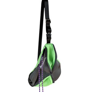 Puede incluir: Una bolsa de bandolera de malla verde y gris con una correa negra ajustable. La bolsa tiene un pequeño bolsillo en la parte delantera con el texto "Arc'teryx" impreso en él.