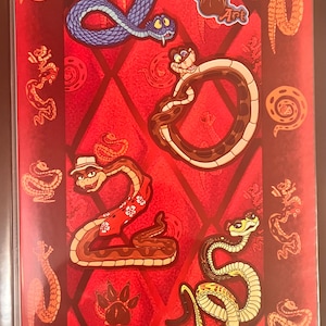 May include: A red poster featuring the number 2025 formed by four cartoon snakes. The snakes are blue, brown, and yellow, with one wearing a hat and floral shirt. The background has a diamond pattern and small orange snake illustrations.
