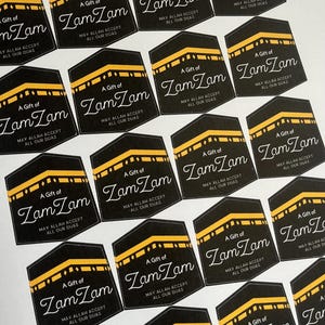 May include: A set of 16 black and gold stickers with the text "A Gift of Zam Zam" and the phrase "May Allah Accept All Our Duas".