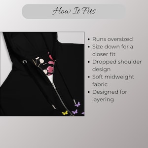 May include: Black zip-up hoodie with a floral and butterfly pattern on the inside lining. The hoodie has a drawstring hood and a silver zipper. The text "How It Fits" is at the top of the image.