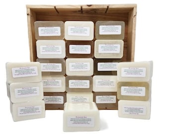 Puede incluir: Una caja de madera llena de barras de jabón rectangulares. Los jabones son de varios tonos de blanco, crema y marrón, cada uno con una etiqueta blanca. La caja es de madera clara.