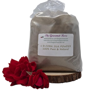 Könnte beinhalten: Ein Beutel mit Maisseidenpulver, beschriftet mit "1 lb CORN SILK POWDER 100% Pure & Natural". Der Beutel steht auf einer Holzscheibe, mit roten Rosen im Vordergrund. The Gourmet Rose ist auf dem Etikett aufgedruckt.