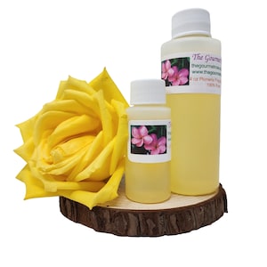 May include: Two clear bottles of liquid with white caps, one large and one small, with labels featuring pink flowers. A large yellow rose and a wooden slice are also in the image. The text on the label reads "The Gourmet".