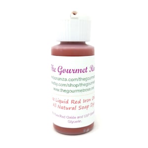 May include: A small bottle of liquid red iron oxide soap dye. The bottle has a white cap and a label with the text "The Gourmet Rose" and product information. The dye is all natural and contains red oxide and glycerin.