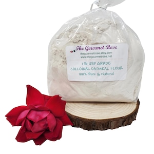 May include: A clear plastic bag filled with colloidal oatmeal flour, labeled "1 lb USP Grade, 100% Pure & Natural." A red rose rests on a wooden slice in the foreground. The Gourmet Rose Etsy shop logo is visible.