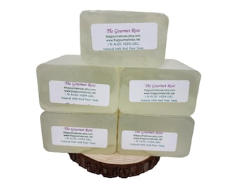 May include: Six clear, rectangular bars of soap stacked on a wooden slice. Each bar has a white label with the text "The Gourmet Rose," website information, and "1 lb ALOE VERA GEL Natural Melt And Pour Soap."