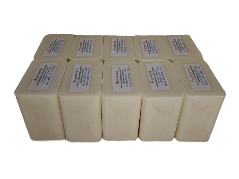 May include: Ten rectangular bars of creamy white soap are displayed. Each bar features a label with the text "The Gourmet Bar" and other details. The arrangement suggests a focus on natural skincare products, with a clean and simple aesthetic.