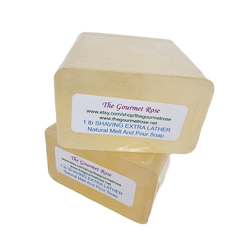 May include: Two rectangular bars of natural melt and pour soap, wrapped in clear plastic. Each bar has a label that reads "The Gourmet Rose" and "1 lb SHAVING EXTRA LATHER". The soap has a light yellow hue.