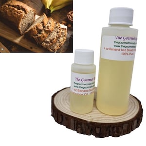 Könnte beinhalten: Ein Brot aus Bananen und Nüssen mit Scheiben auf einem Holzbrett und zwei Flaschen Duftöl. Die Flaschen sind mit "The Gourmet Rose" und "Banana Nut Bread Fragrance Oil" beschriftet. Die Flaschen stehen auf einer Holzscheibe.