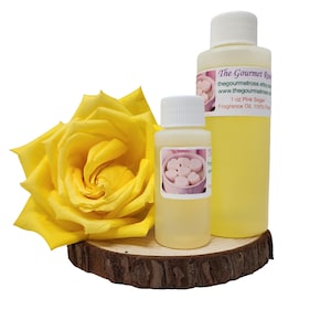 May include: A yellow rose and two bottles of fragrance oil on a wooden slice. The bottles have white caps and labels that read "The Gourmet Rose" and "1 oz Pink Sugar Fragrance Oil, 100% Pure". The oil is a pale yellow colour.