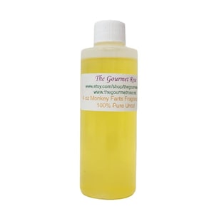 May include: A clear plastic bottle filled with a yellow liquid, featuring a white cap. A label on the bottle reads "The Gourmet Rose" and lists a website. The label also states "4 oz Monkey Farts Fragrance 100% Pure Uncut."