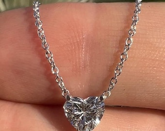 Puede incluir: Un collar de cadena de plata con un colgante de diamante en forma de corazón.