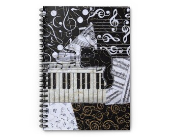 Puede incluir: Cuaderno de espiral con un tema musical en blanco y negro. La portada presenta un gato negro descansando sobre un teclado de piano, con notas musicales y claves de sol en el fondo. El diseño incorpora acentos dorados y una estética de patchwork.