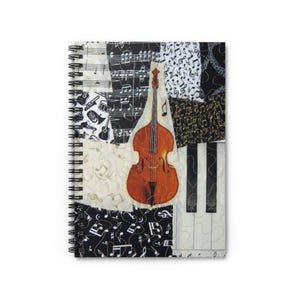 May include: Spiral-bound notebook with a patchwork design featuring musical notes, a double bass, and piano keys. The cover combines black, white, and cream-colored fabric pieces, creating a musical theme.