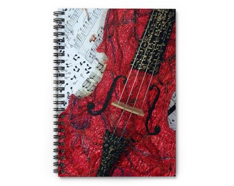 Puede incluir: Cuaderno de espiral con un diseño de violonchelo rojo vibrante. La portada presenta notas musicales y una apariencia texturizada, con detalles en negro y dorado. El diseño del cuaderno es artístico y temático musical.