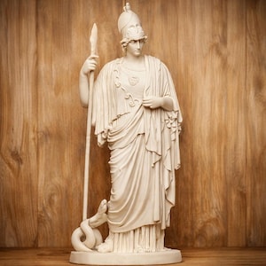 Puede incluir: Estatua de color crema de una figura clásica, sosteniendo una lanza y usando un casco y prendas drapeadas. Una serpiente está enrollada a los pies de la figura. La estatua está sobre un fondo de madera cálida.