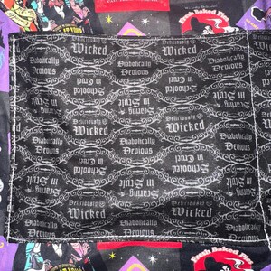 May include: A black and purple fabric with various villain-themed patches and a pocket. The pocket features a repeating pattern with the words "Wicked" and "Diabolically Devious". Other patches include text like "Driving Academy" and "We're at your service".