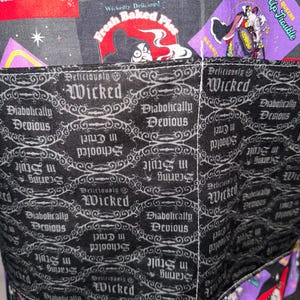 May include: Close-up of a fabric item with a black and gray pattern featuring the word "Wicked" and phrases like "Diabolically Devious." The design includes images and text from a cartoon, with a red and purple color scheme.