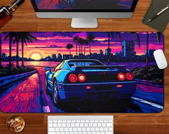 May include: A rectangular desk mat featuring a vibrant illustration of a blue sports car driving along a coastal road at sunset. The scene includes palm trees, a city skyline, and a glowing sun against a purple and orange sky.