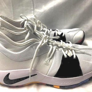 May include: White and black athletic shoes with white laces. The shoes have a black Nike swoosh and a multi-colored sole. The shoes are designed for athletic activities and have a modern, sporty look.