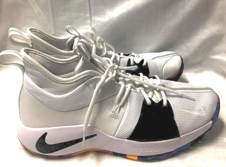May include: White and black athletic shoes with white laces. The shoes have a black Nike swoosh and a multi-colored sole. The shoes are designed for athletic activities and have a modern, sporty look.