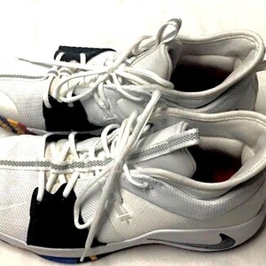 May include: Pair of white and gray athletic shoes with white laces. The shoes have black accents and a gray stripe detail. The soles have a multi-colored design. The shoes are designed for athletic activities.