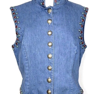 May include: A blue denim vest with a stand-up collar and silver buttons. The vest is decorated with colorful round embellishments around the collar, armholes, and hem.