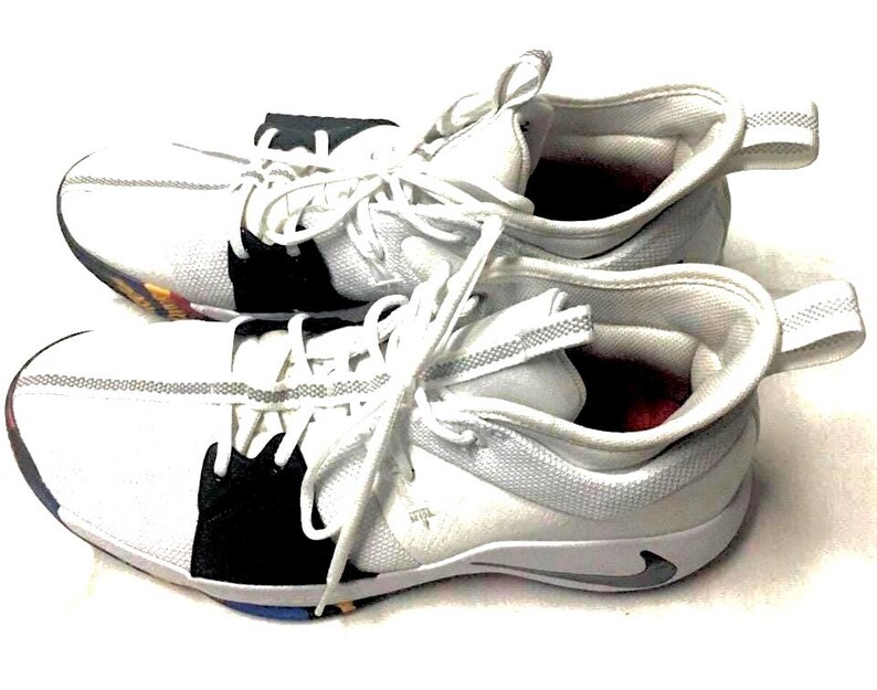 May include: Pair of white athletic shoes with black accents and white laces. The shoes have a low-top design with a pull tab on the heel. The soles have a multi-colored design.
