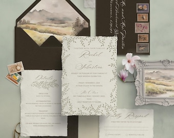 May include: Rustic wedding invitation suite with a watercolor landscape design. The invitation features a leafy border and the text "Rachel and Sebastian request the pleasure of your company at their wedding celebration". The RSVP card has a floral design and the text "Kindly Respond".