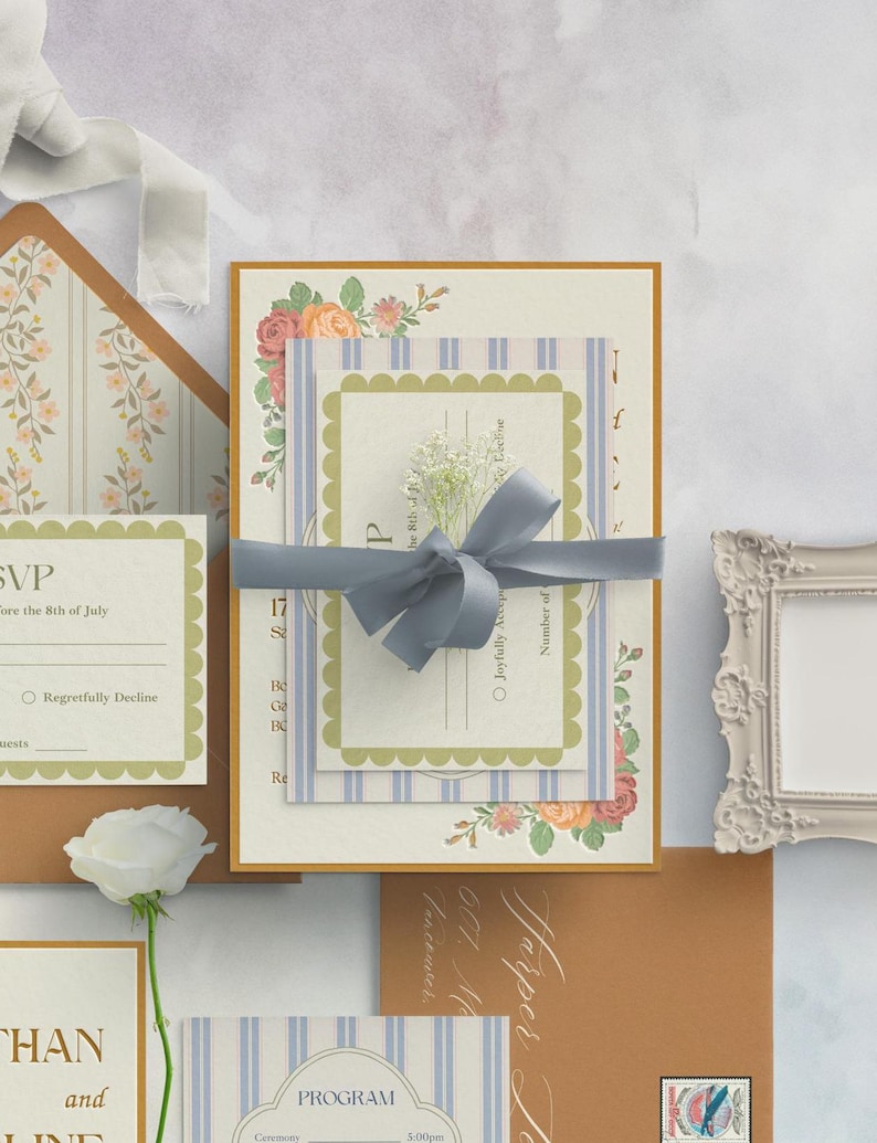 Puede incluir: Un conjunto de invitaciones de boda con un patr&oacute;n a rayas azul y blanco, acentos florales y una tarjeta RSVP. La invitaci&oacute;n incluye el texto "Harper & Logan" y "601 Main Street, Vancouver".