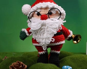 Könnte beinhalten: Eine gehäkelte Weihnachtsmannfigur, bekleidet mit einem roten Anzug mit weißer Bordüre, einem passenden Hut und schwarzen Stiefeln. Die Figur hat einen weißen Bart, eine runde Brille und hält eine goldene Glocke. Der Hintergrund ist grün.