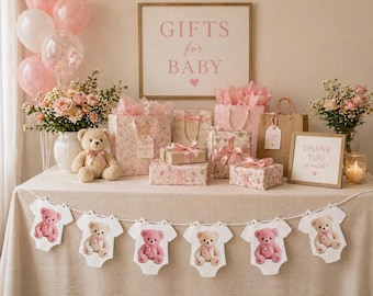 Op de afbeelding: Een babyborrel display met cadeaus, ballonnen en bloemstukken. Een slinger van rompertjes met teddyberen hangt voor een tafel met ingepakte cadeaus, cadeauzakken en een bord met de tekst "Gifts for Baby". Een teddybeer zit op de tafel.