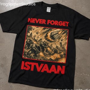 May include: Black t-shirt with the words "NEVER FORGET ISTVAAN" in red block letters. The shirt features a detailed illustration of a battle scene with soldiers, explosions, and falling objects. The artist's name, @FrogSpawnStudios, is in the bottom right corner.