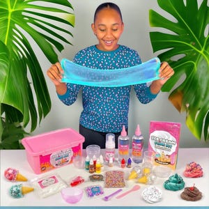 Puede incluir: Un contenedor de plástico rosa con las palabras "Ice Cream Slime Kit" en la parte delantera. El kit incluye una variedad de ingredientes para hacer slime, incluyendo pegamento, purpurina y espolvorear. También hay varias botellas pequeñas de líquido, un vaso de plástico transparente y un tazón pequeño. El kit está sobre una mesa con una variedad de otros suministros para hacer slime, incluyendo un slime azul, un slime verde y un slime marrón.