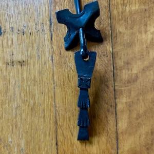 May include: Black metal door handle with a decorative design. The handle is attached to a metal plate with four points.