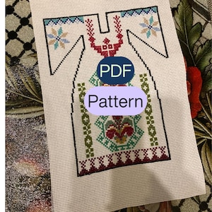 May include: A cross-stitch pattern on white fabric, featuring a geometric design in red, green, blue, and black. The word "Pattern" is displayed in a light purple oval, with "PDF" in a blue oval above it.