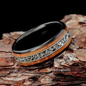 May include: A black and brown ring with a silver inlay design. The ring is made of wood and metal.