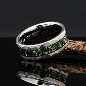 May include: A silver tungsten carbide ring with a green and white inlay. The ring has a textured, diamond-shaped pattern.