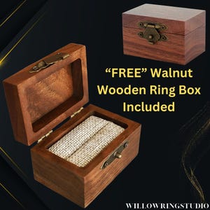 Pu&ograve; includere: Due scatole portanelli in legno di noce, una aperta e una chiusa, con chiusure in ottone. La scatola aperta rivela un interno in tessuto beige per anelli. Il testo recita "FREE Walnut Wooden Ring Box Included".
