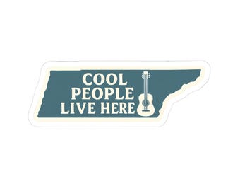 Pode incluir: Um autocolante com o texto "COOL PEOPLE LIVE HERE" em letras maiúsculas brancas, com um desenho de guitarra. O design está sobre um fundo verde-azulado em forma do estado do Tennessee, com uma borda branca.
