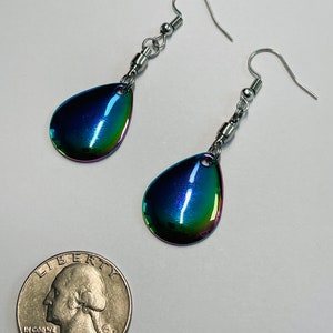 May include: A pair of iridescent teardrop-shaped earrings with silver hooks and a silver chain. The earrings are about the size of a quarter.