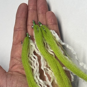 May include: Three fishing flies with bright green and white synthetic fibers. Each fly has a small hook and a green thread head. The flies are displayed on a light background.