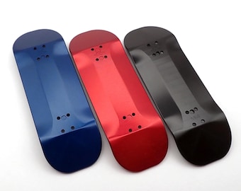 Könnte beinhalten: Drei Fingerboards in Blau, Rot und Schwarz. Die Fingerboards bestehen aus einem glatten, harten Material und haben eine leicht konkave Form. Jedes Fingerboard hat ein kleines, rundes Loch in der Mitte.