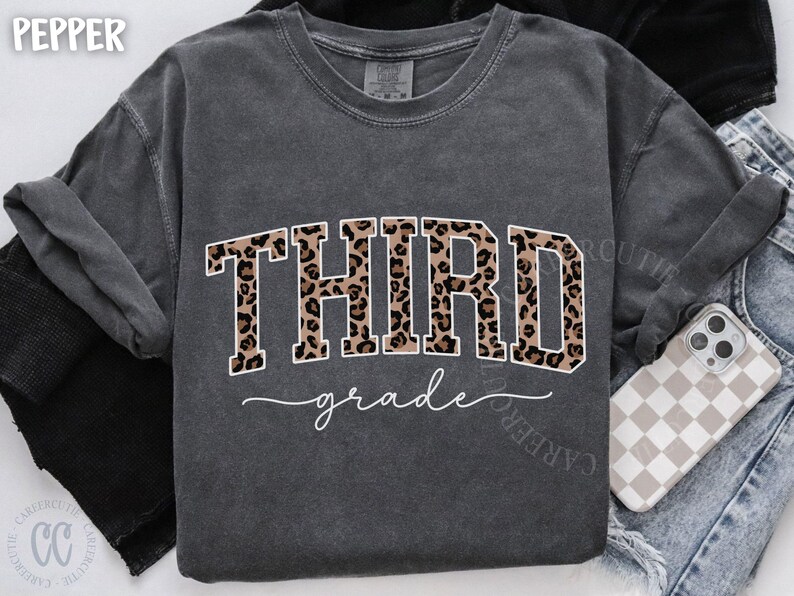 May include: Dark gray sweatshirt with the word "THIRD" in leopard print and "grade" in cursive. The shirt is a comfortable, casual style, perfect for back-to-school or everyday wear.