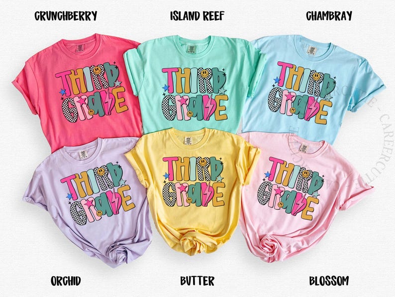 May include: A collection of six colorful t-shirts, each in a different pastel shade: pink, light blue, yellow, lavender, light green, and pink. Each shirt features the words "THIRD GRADE" in a playful, multi-colored design with stars and a lightning bolt.
