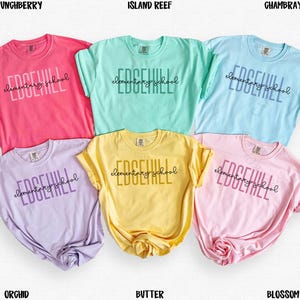 May include: A collection of six t-shirts in various colors: pink, mint green, light blue, lavender, yellow, and light pink. Each shirt features the text "EDGEHILL elementary school" in a contrasting color.